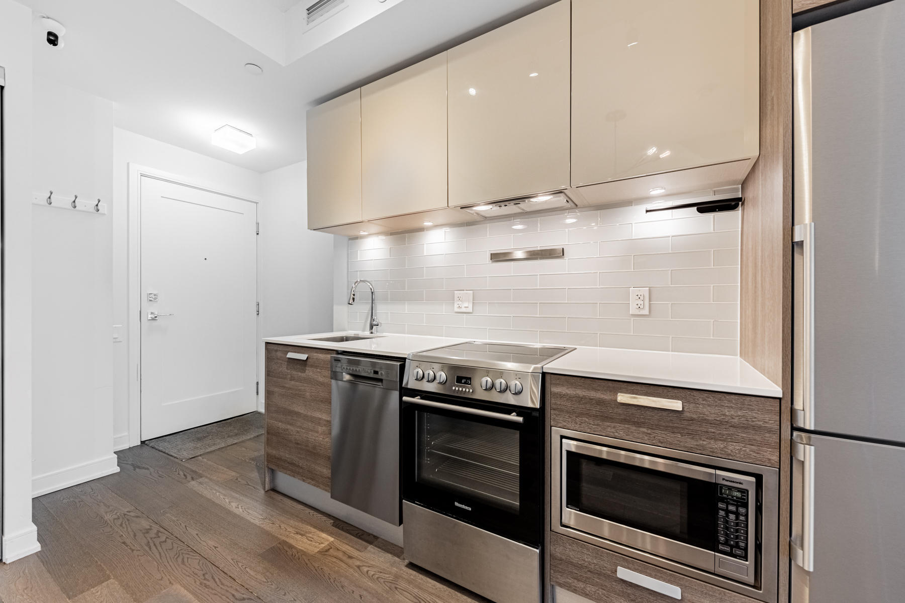 57 St Joseph Street Unit 523 linear kitchen with 2-tone cabinet colours, subway-tile back-splash and white counters.