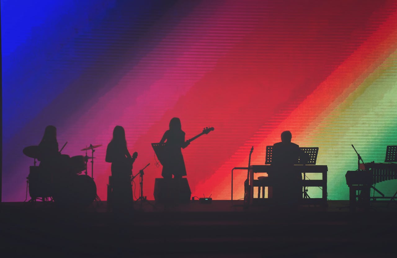 Black silhouettes on colourful background of band performing on stage.