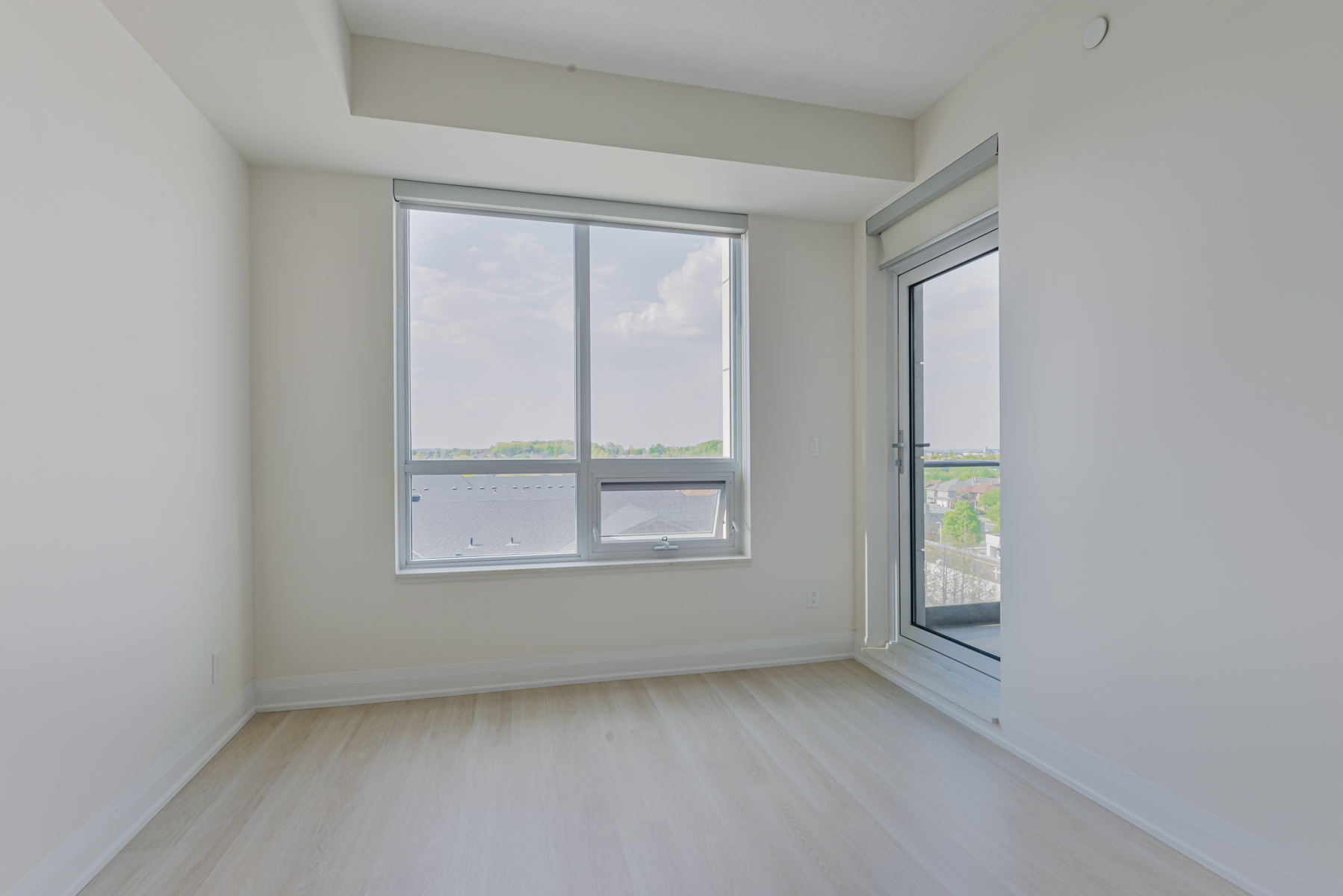 Condo living room with large window and balcony overlooking ravine. 