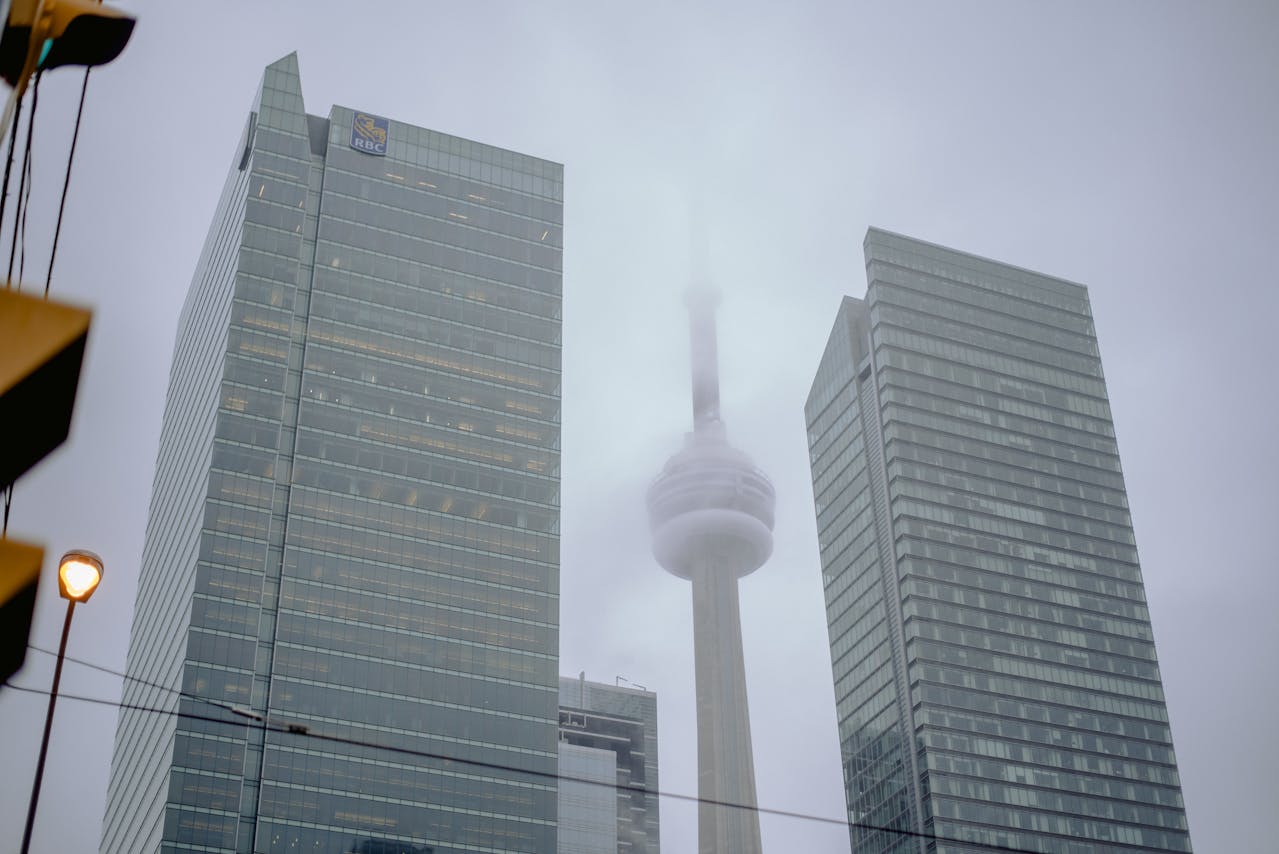 Hazy CN Tower between two buildings to show difficulty of forecasting 2025 GTA Housing Market.