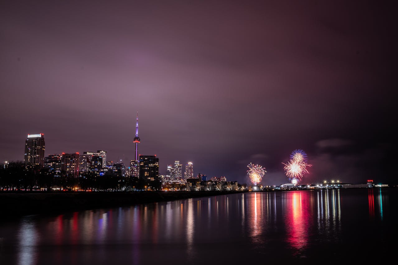 Toronto skyline at night with fireworks display to show upcoming 2025 GTA housing market. 