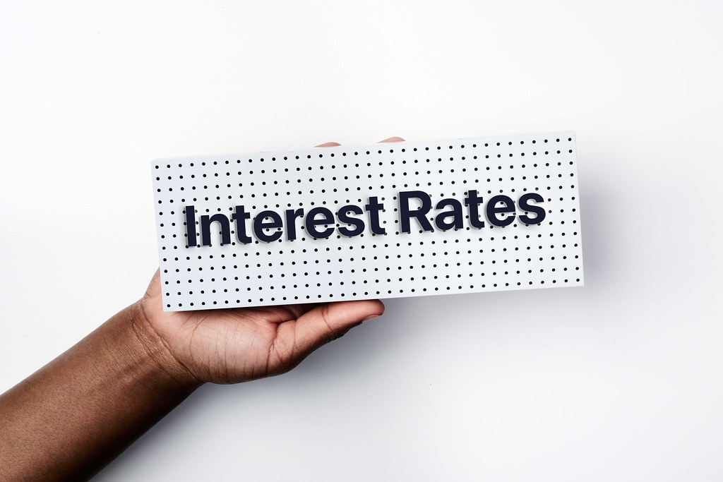 Hand holding sign with words “Interest Rates.”