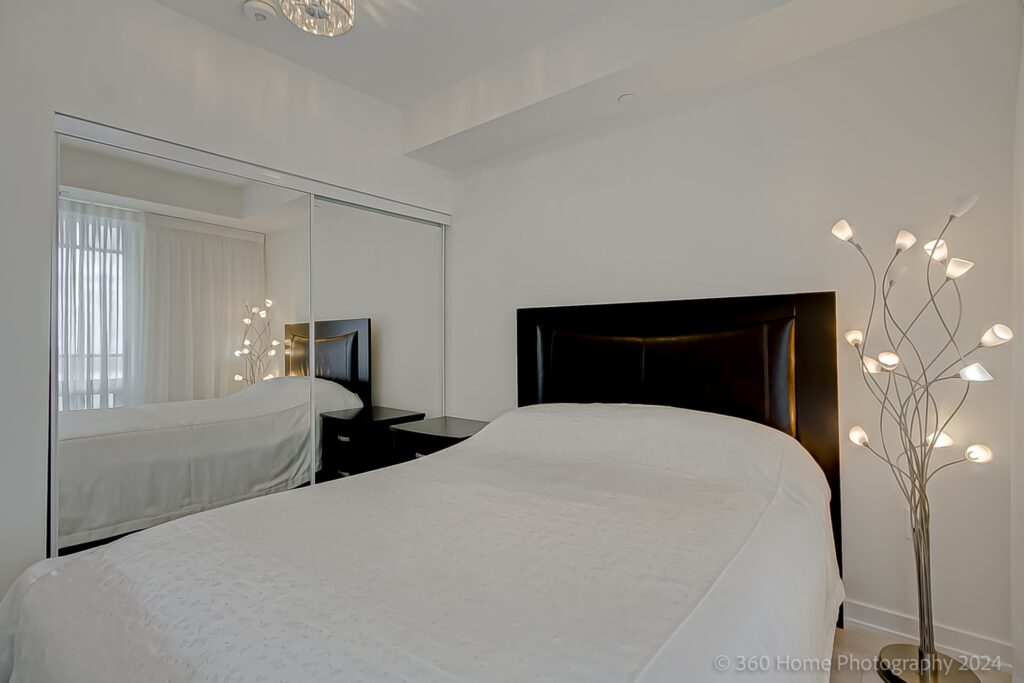 Condo bedroom with custom-built mirror door closets.