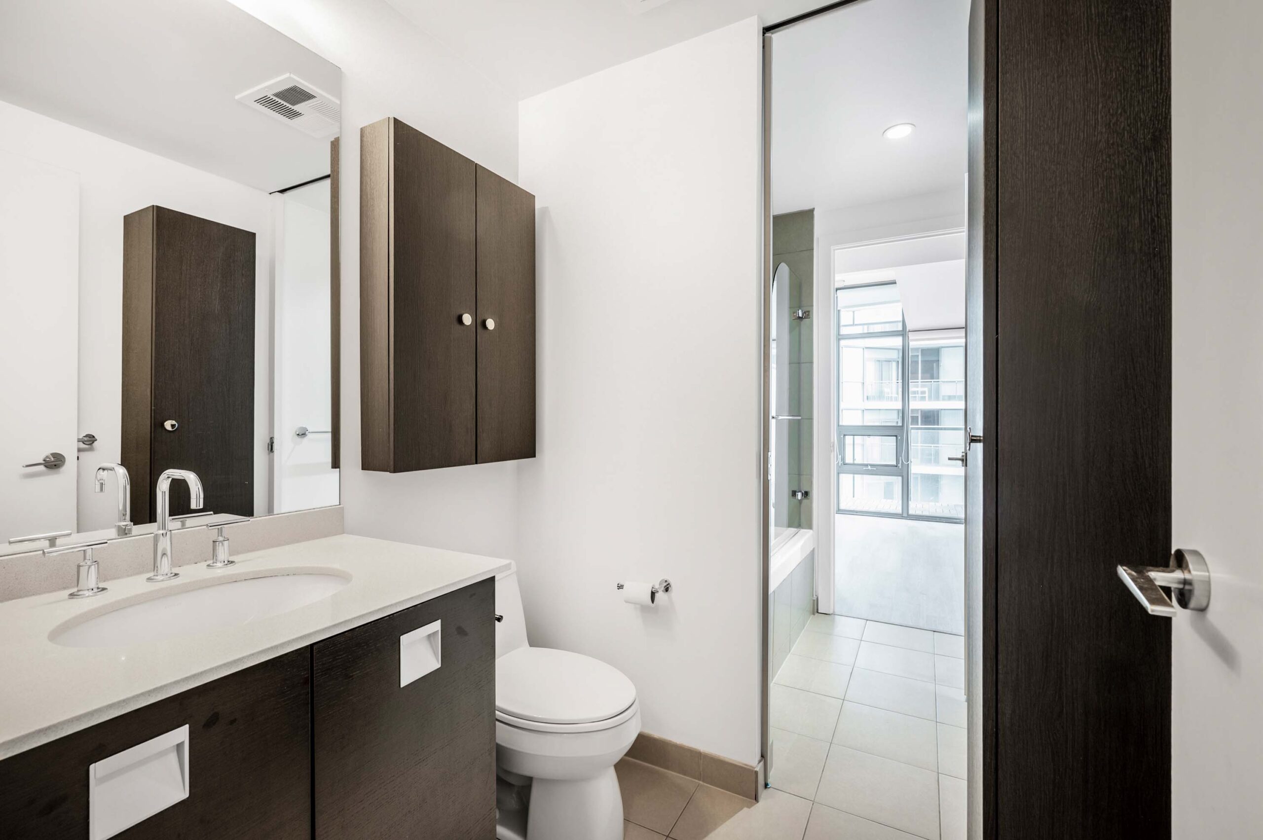 Bathroom with tiled floors and tall vanity with cabinets.