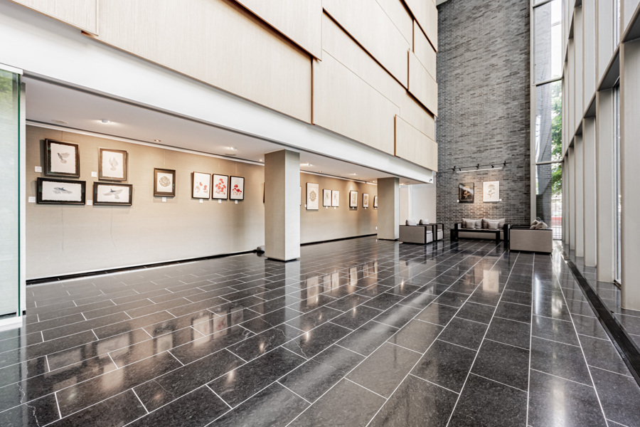 Luxurious condo lobby with black tiles, brick wall and furniture by Armani Casa.
