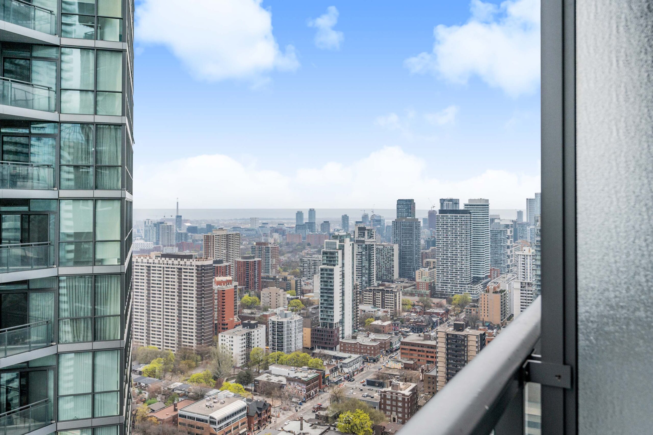 View of low and mid-rise buildings in downtown Toronto plus glimpse of Lake Ontario in distance.