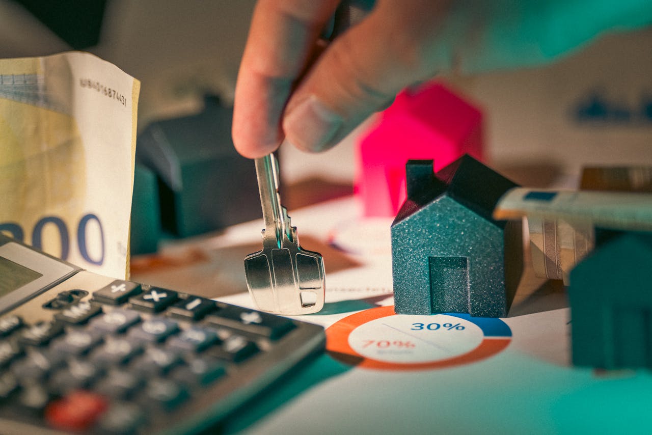 Photo of key, calculator and miniature home to show cost of owning home.