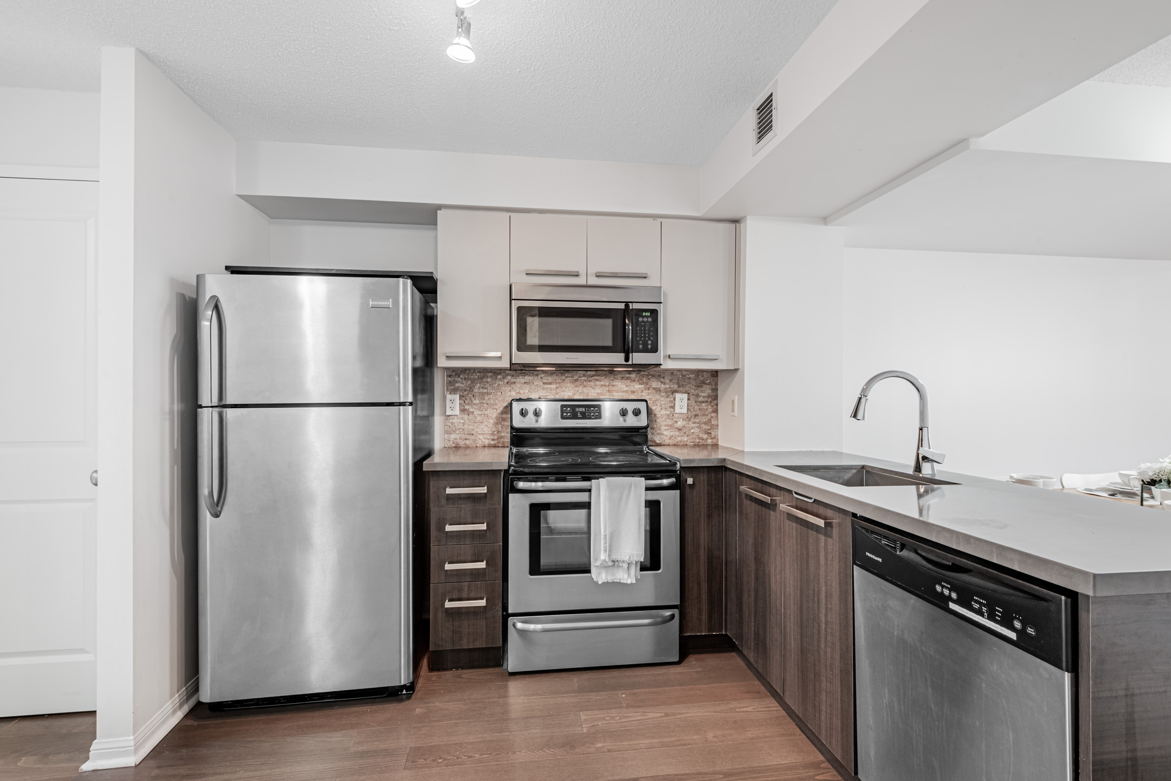 Condo kitchen with natural stone back-splash arranged in mosaic tiles.
