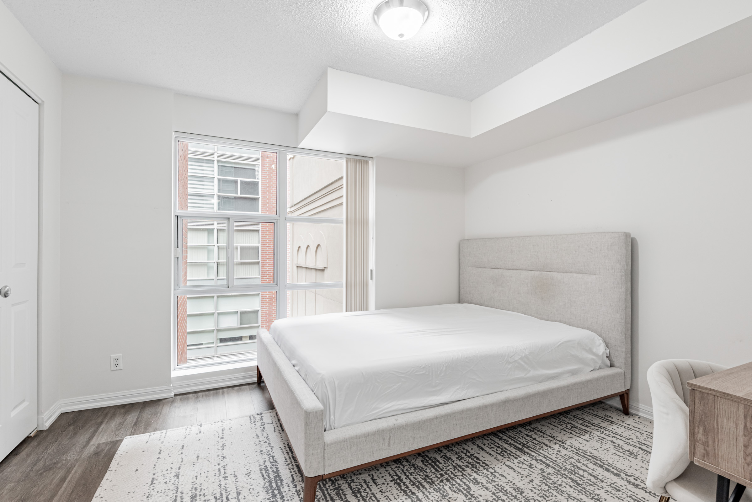 11 St Joseph St Unit 311 spacious primary bedroom with queen-sized bed and large windows.