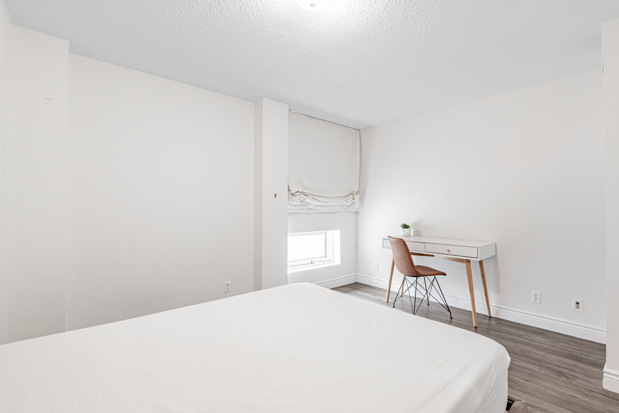 Condo bedroom with desk and chair close to window.