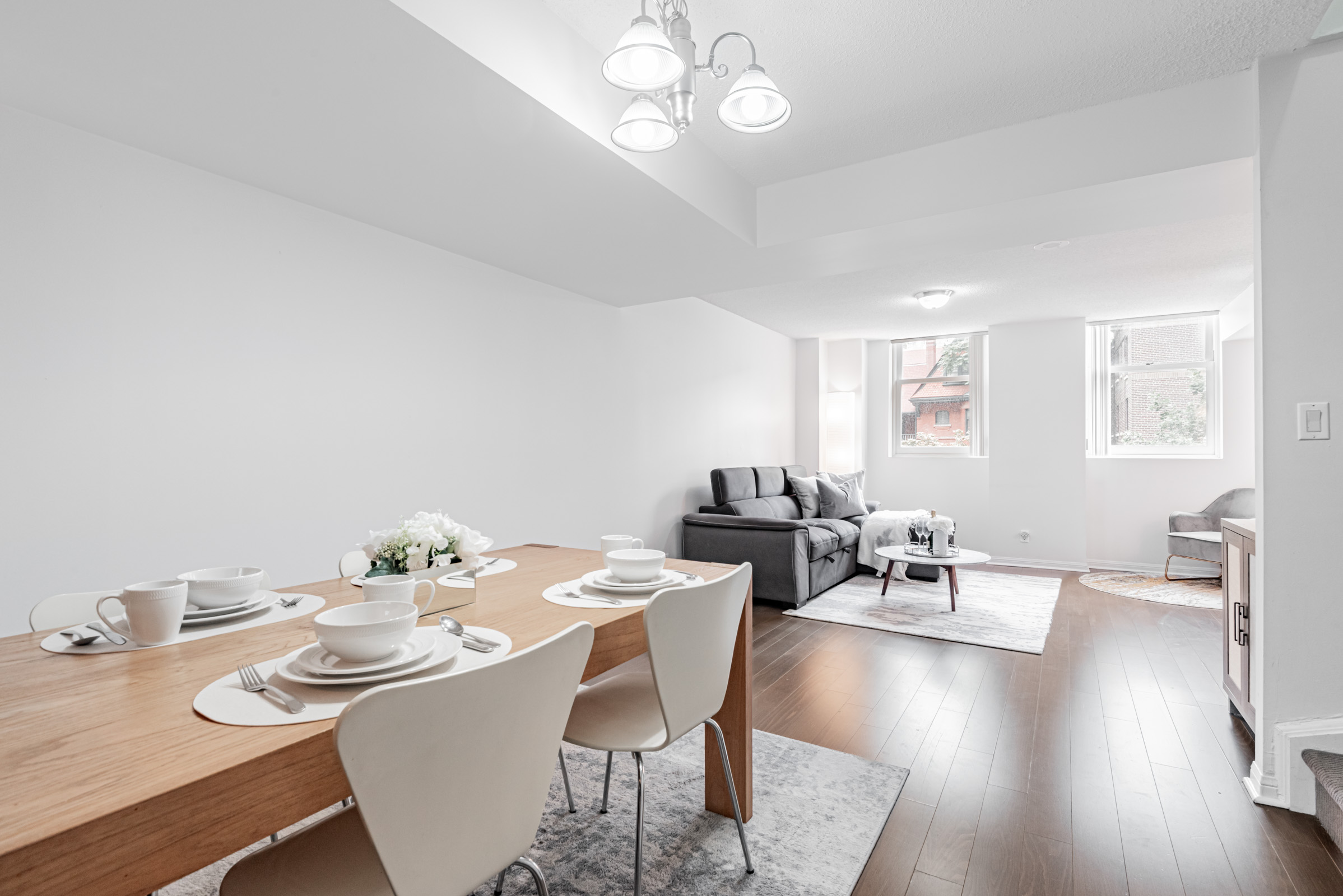 Condo dining room with silver chandelier with natural light from living room.
