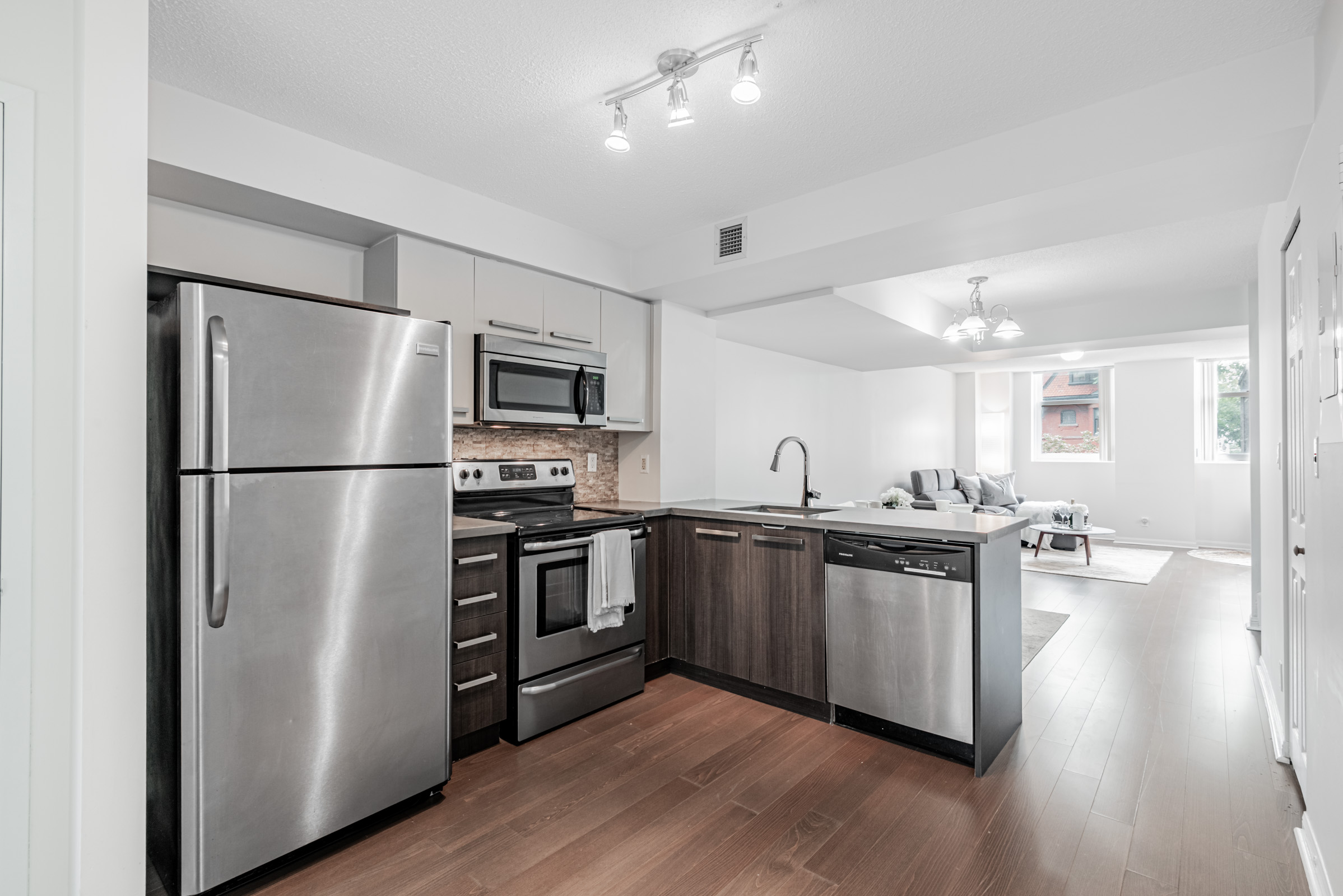 Kitchen of 11 St Joseph St Unit 311 with stainless steel appliances and earth-toned cabinets and floors.