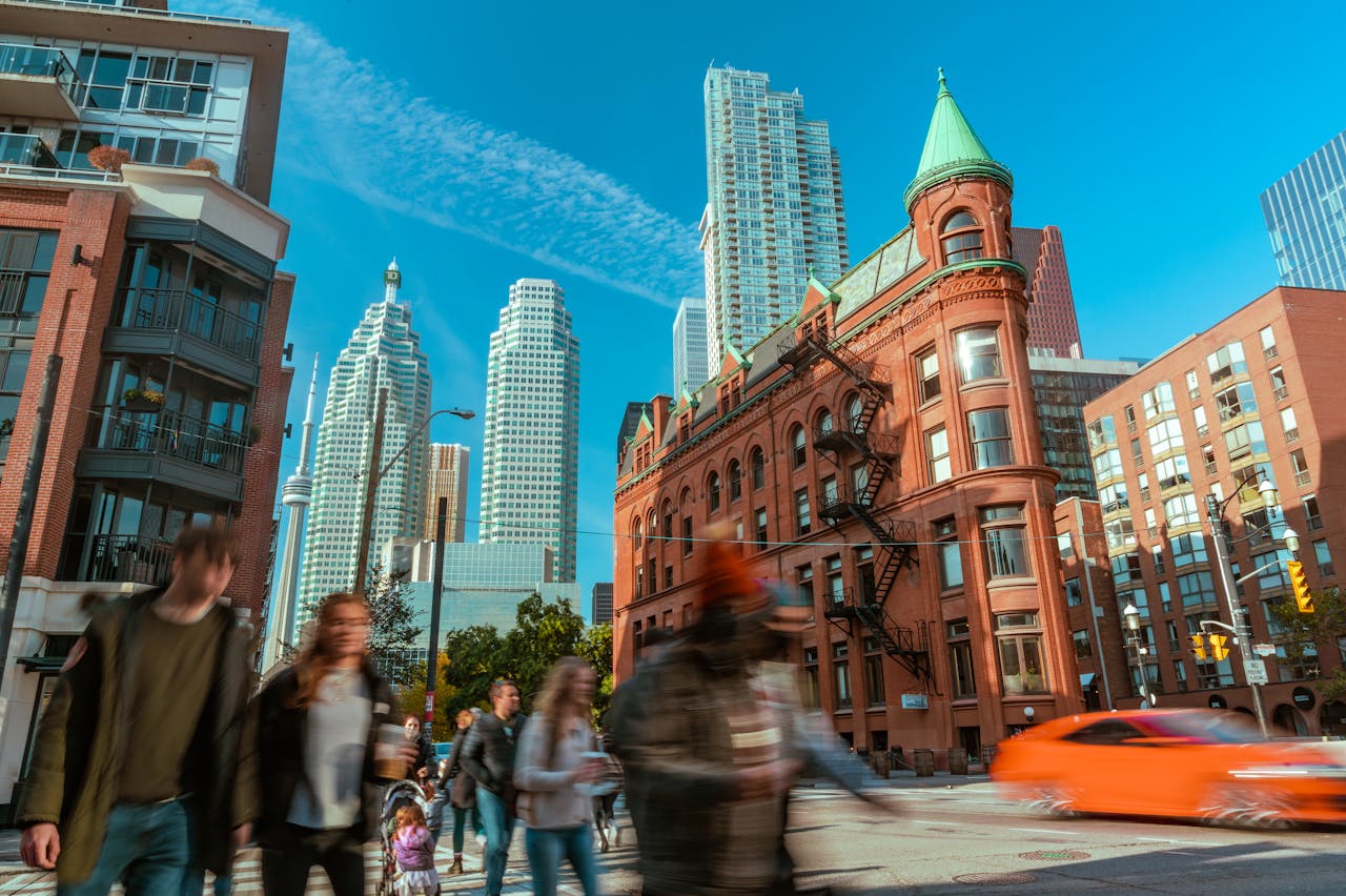 Blurred pedestrians in front of Toronto's flatiron building to show uncertainty following September 2025 rate cut.