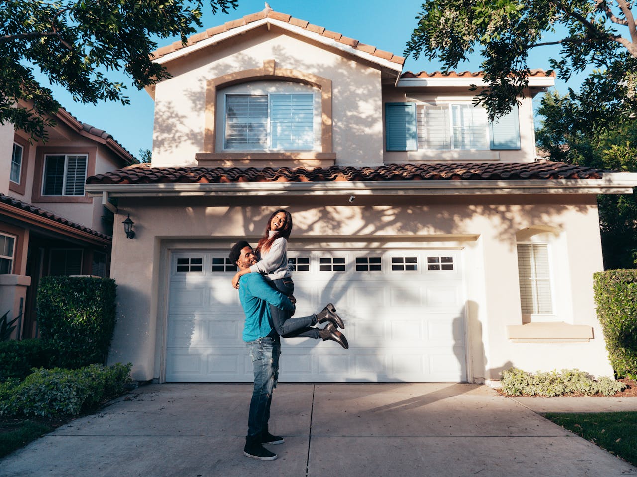 Joyous young interracial couple in front of house to show relief from September 2025 rate cut.