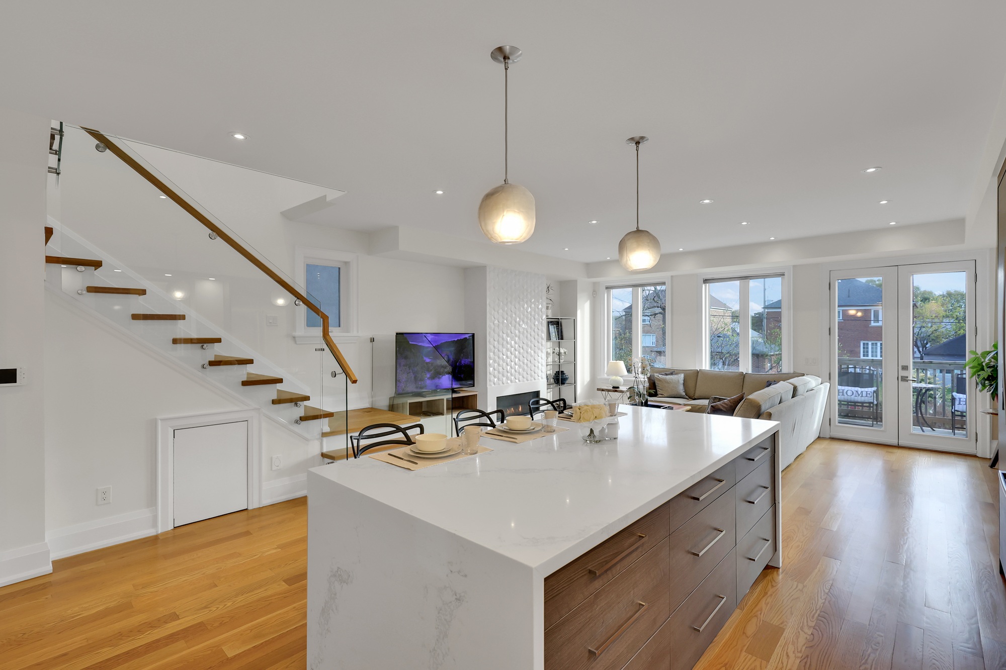 Kitchen island lit by pendant lights, with a polished white surface and dark brown wooden side cabinets.