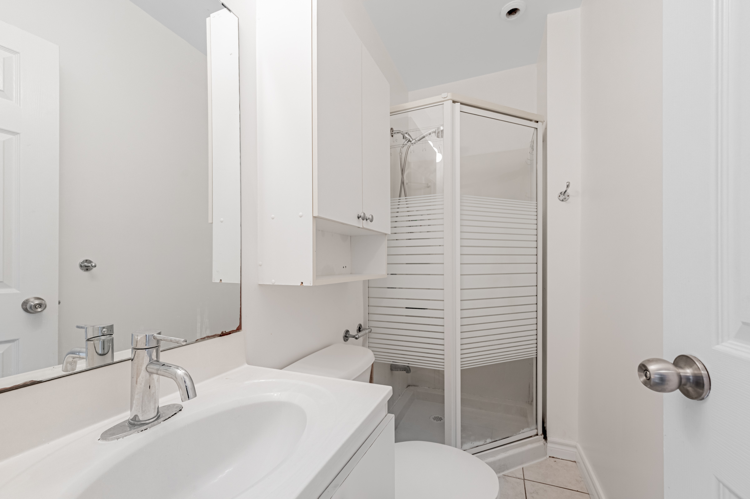 42 Carr St 3-piece bathroom with tiled floors, sink with storage, wall-mounted medicine cabinet, and walk-in shower with detachable showerhead.