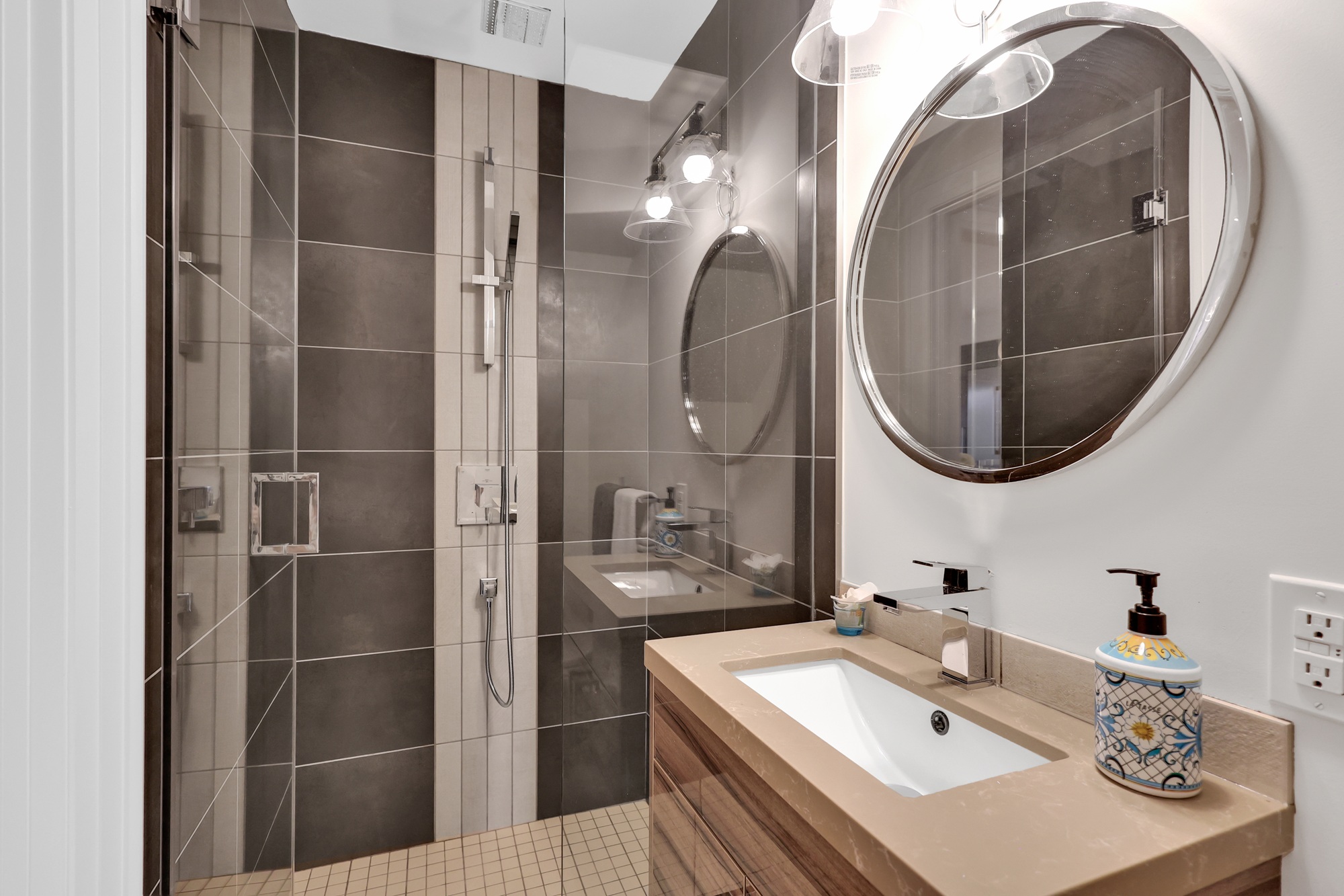 743 Glencairn Ave 3-piece main floor bath with contemporary light and shower fixtures, dark and light tiles, frameless glass shower, and glossy vanity.