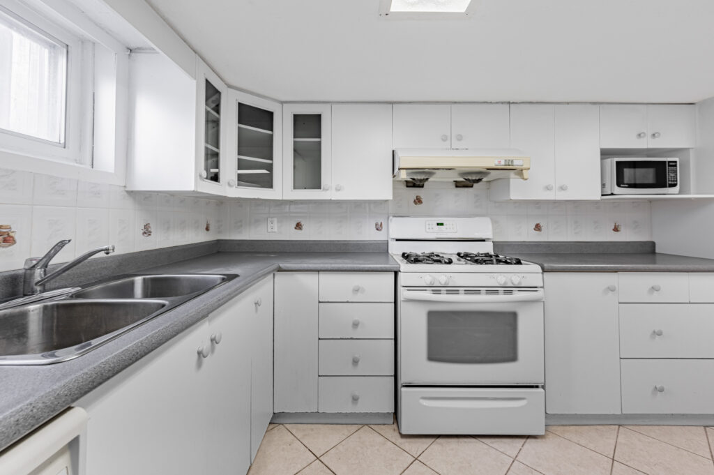 Kitchen with dark gray counters that contrast against white cabinets and backsplash.