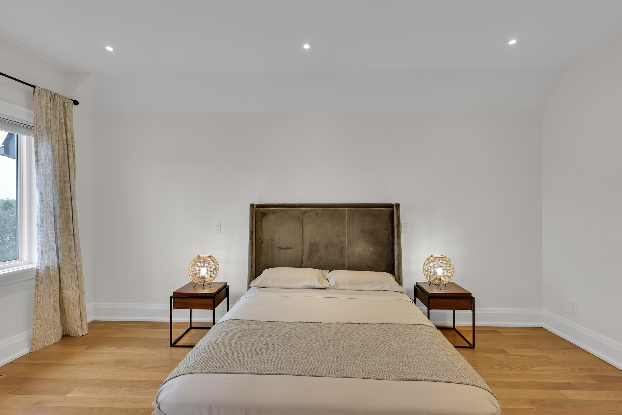 Empty looking primary bedroom with large bed and two side tables.