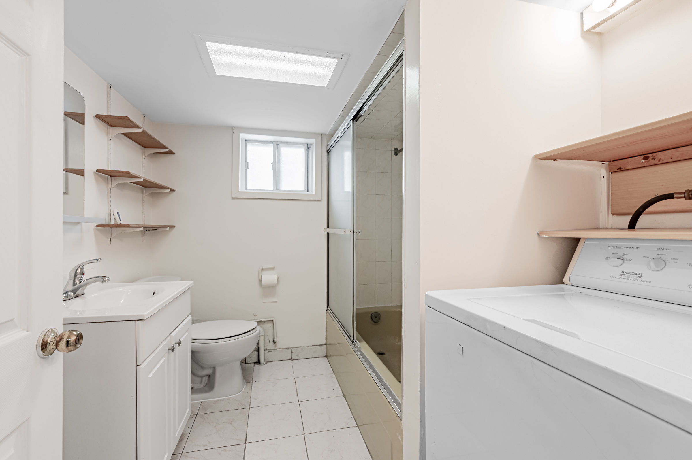 4-piece bath with wall-mounted shelves, floor and ceiling tiles, built-in vanity, and tub with sliding glass door.