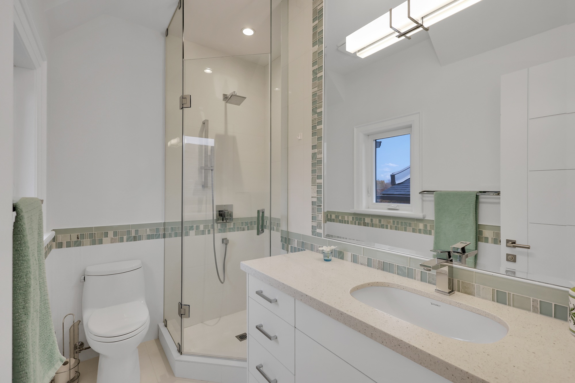 3-piece ensuite bath with frameless glass shower, quartz counters, under-sink storage, and mirror mounted vanity lights. 