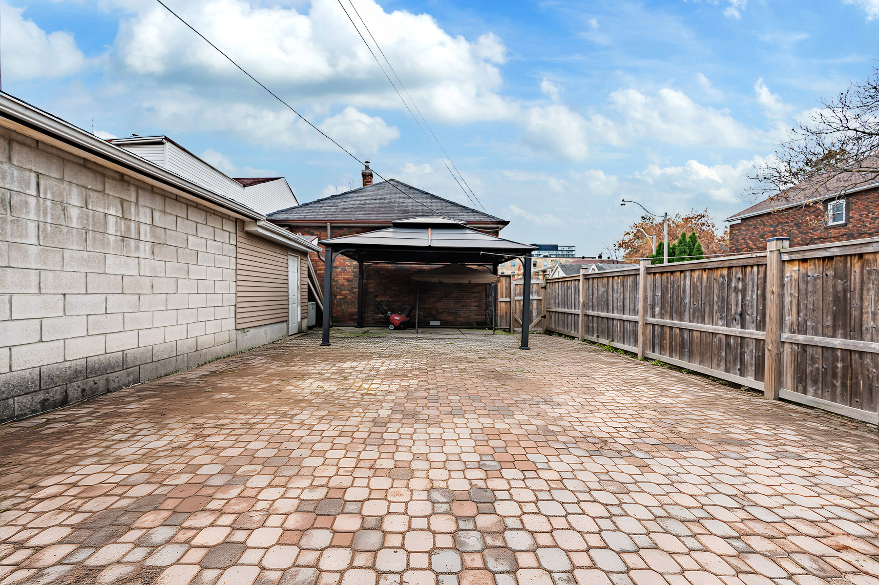 Large backyard with black metal carport.