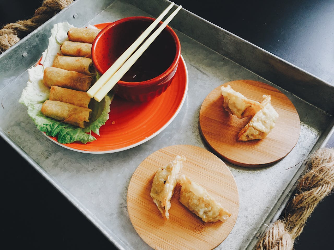 Tin platter with red plate, bowl, chopsticks, and dumplings. 