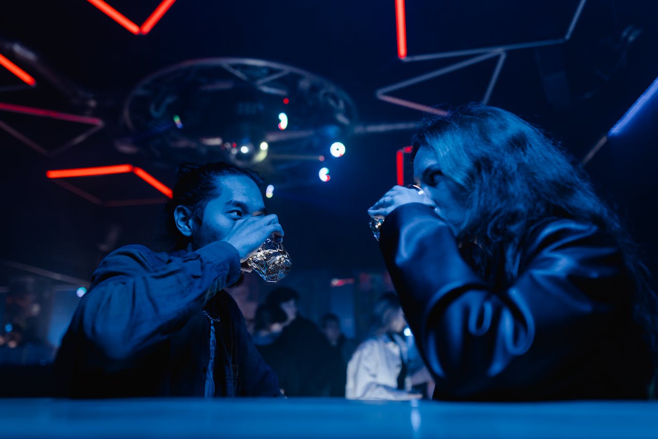 Young man and woman drinking in a dark nightclub. 