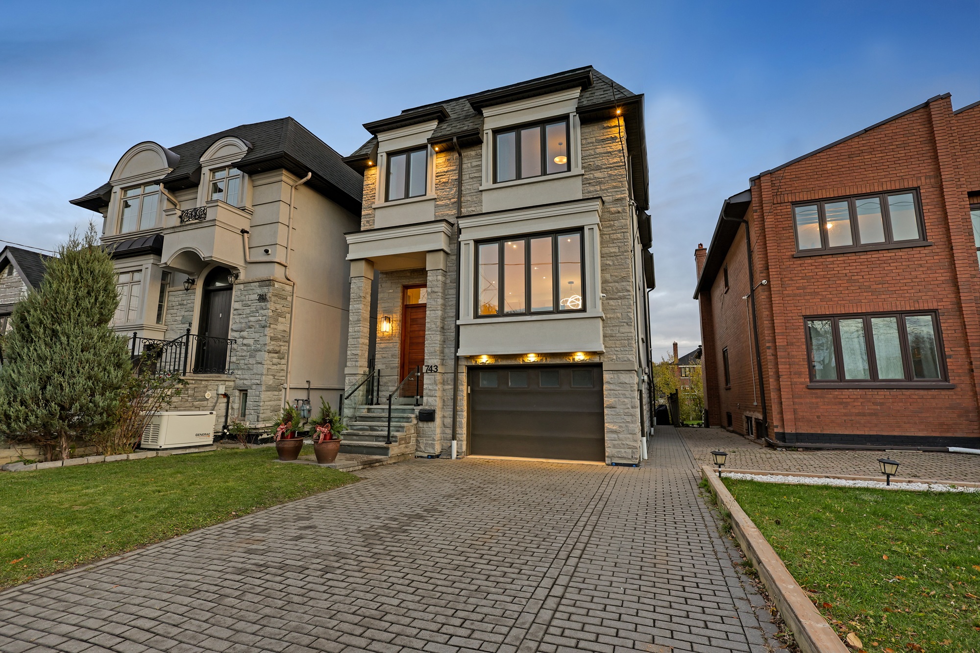 743 Glencairn Ave lit by garage downlights, sconces, and under-eave lights at twilight.