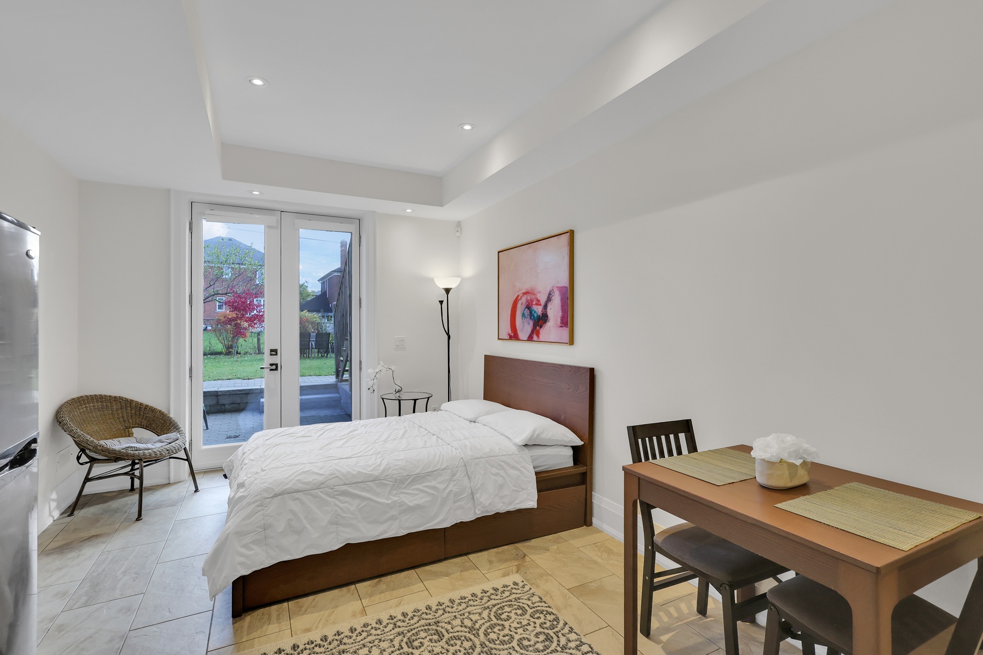 Basement bedroom with door leading into lush backyard. 