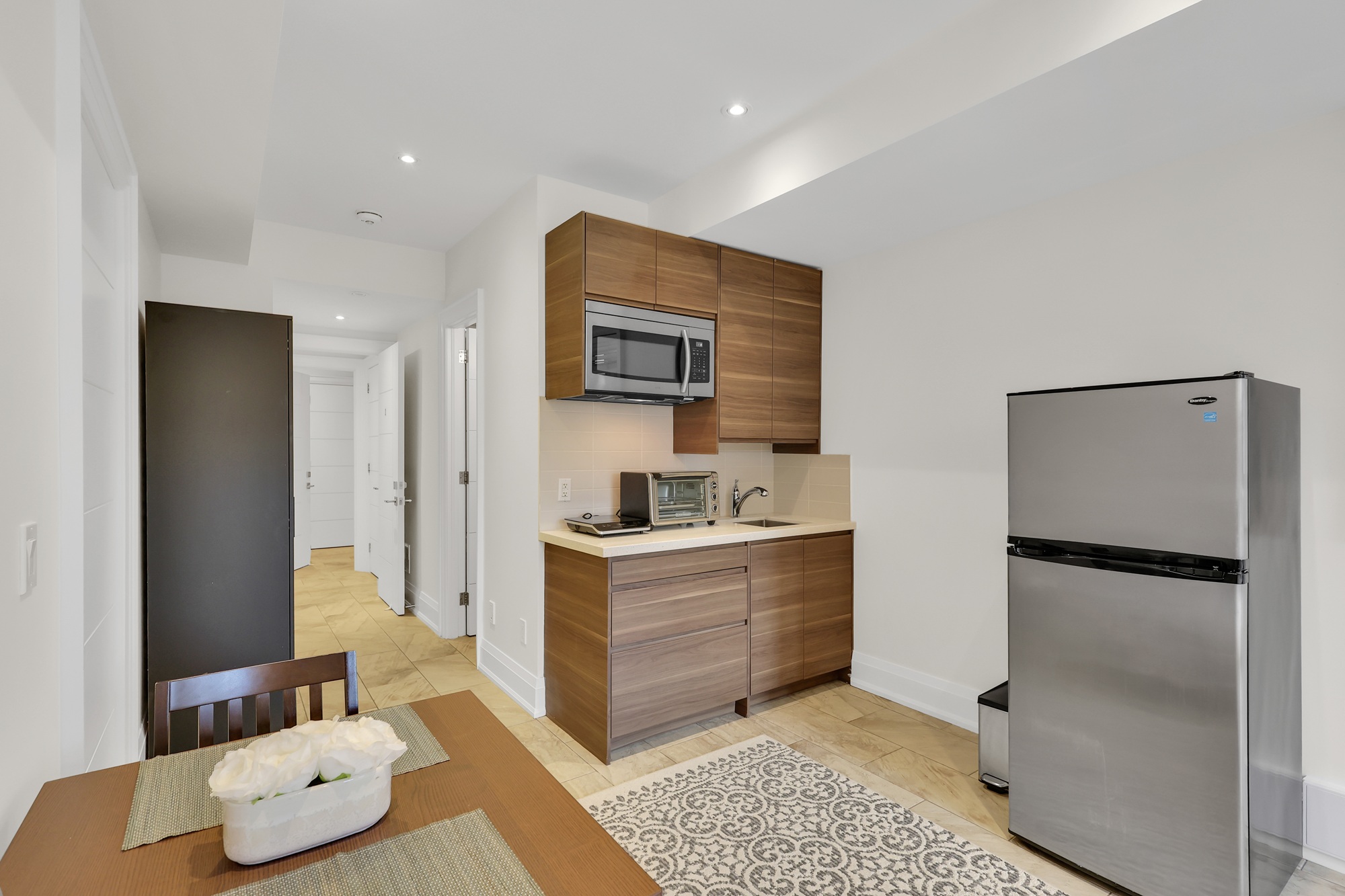 Basement kitchenette with storage cabinets, sink, microwave, and counter with small appliances.