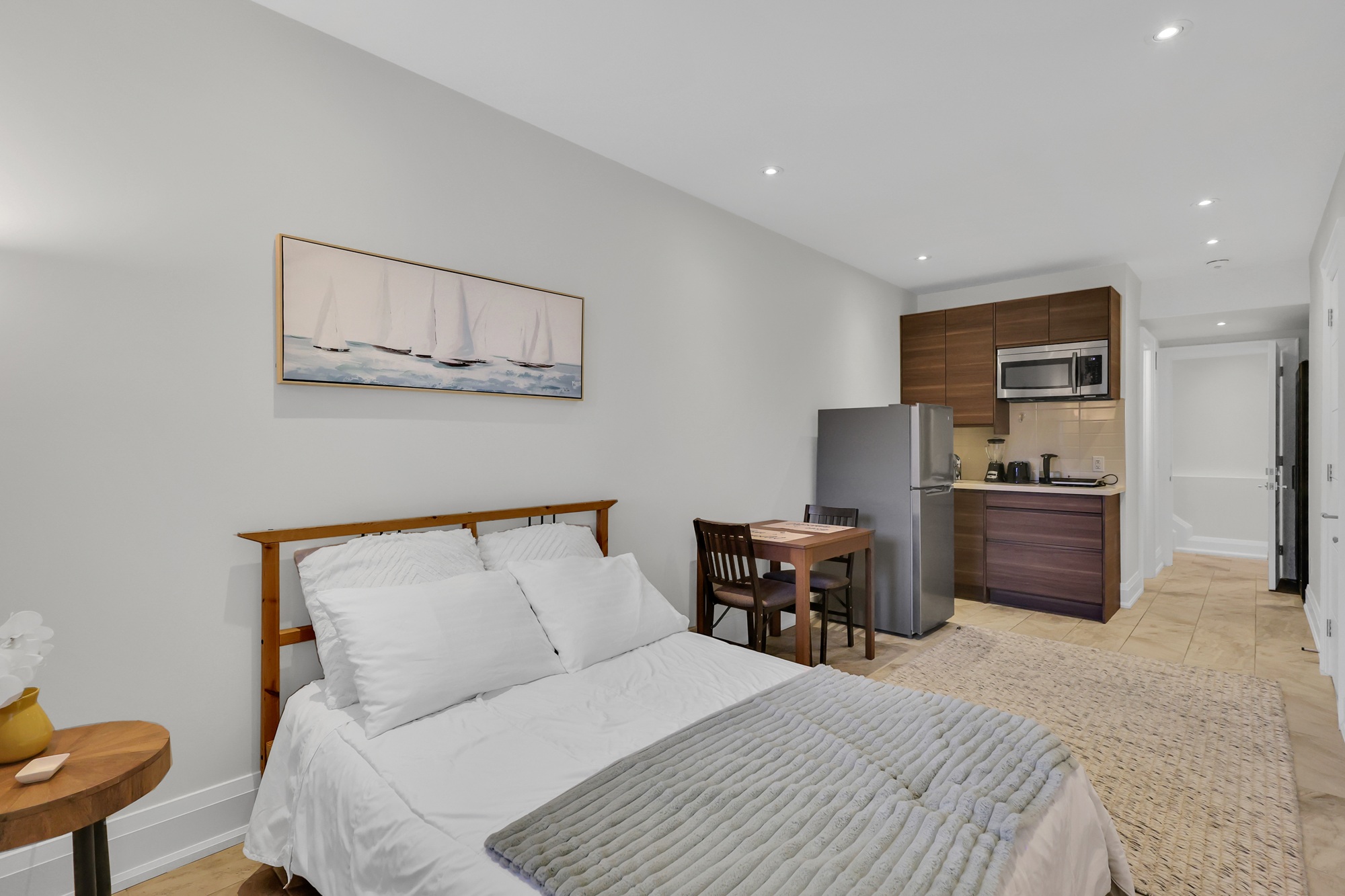 Basement studio unit with streamlined open-concept bedroom, dining room and kitchenette.
