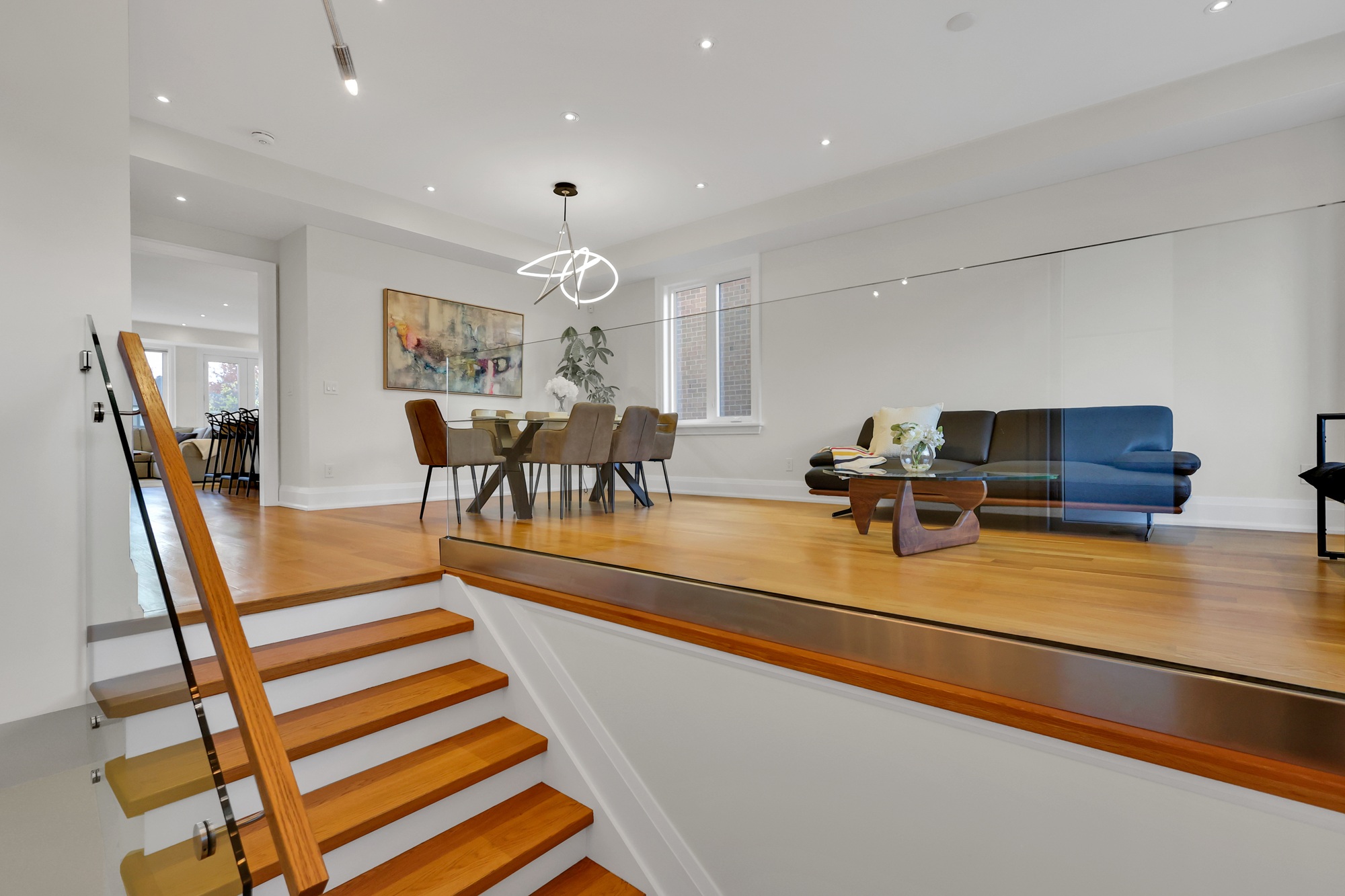 Staircase with wooden rails and glass banister leading up to main floor.