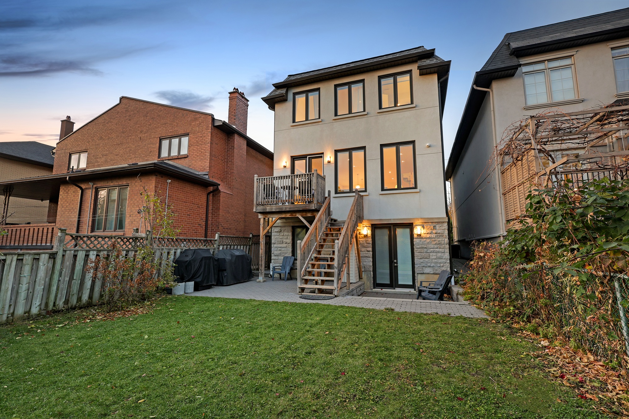 House backyard illuminated by lights at dusk.