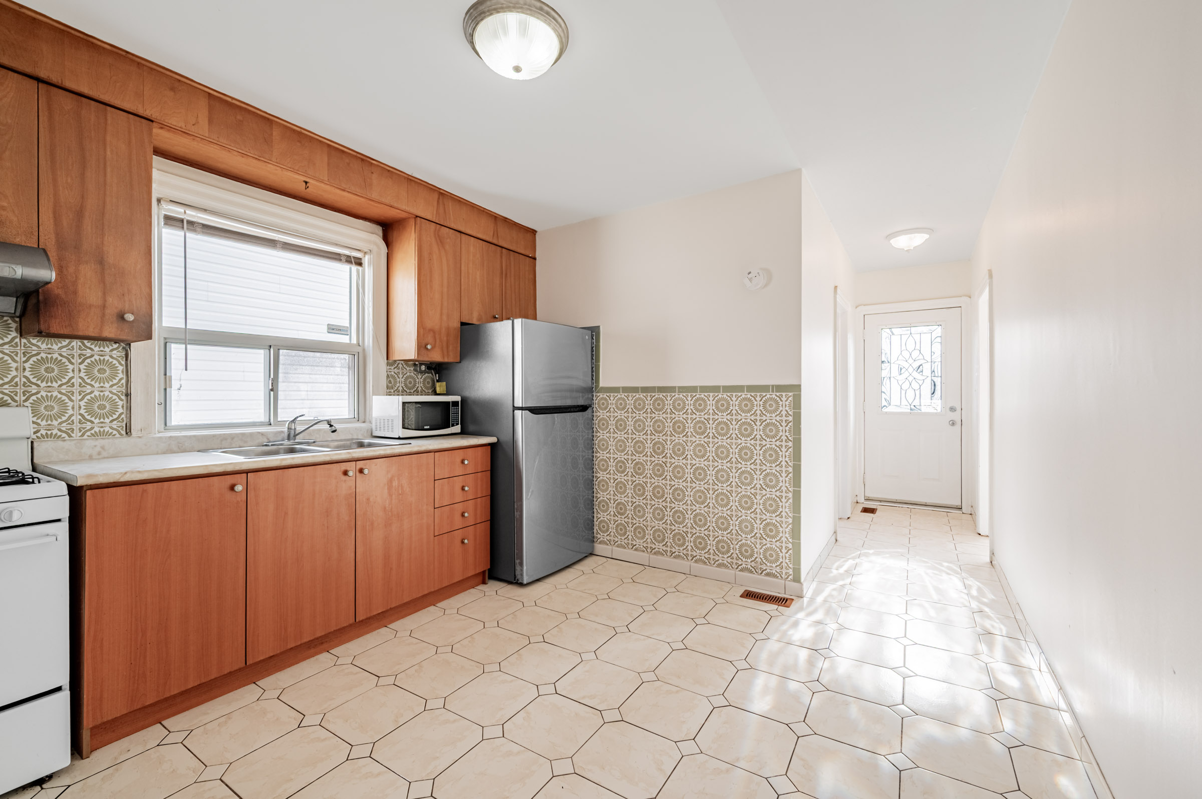 House kitchen and hallway with intricately patterned tiles on floor and wall.