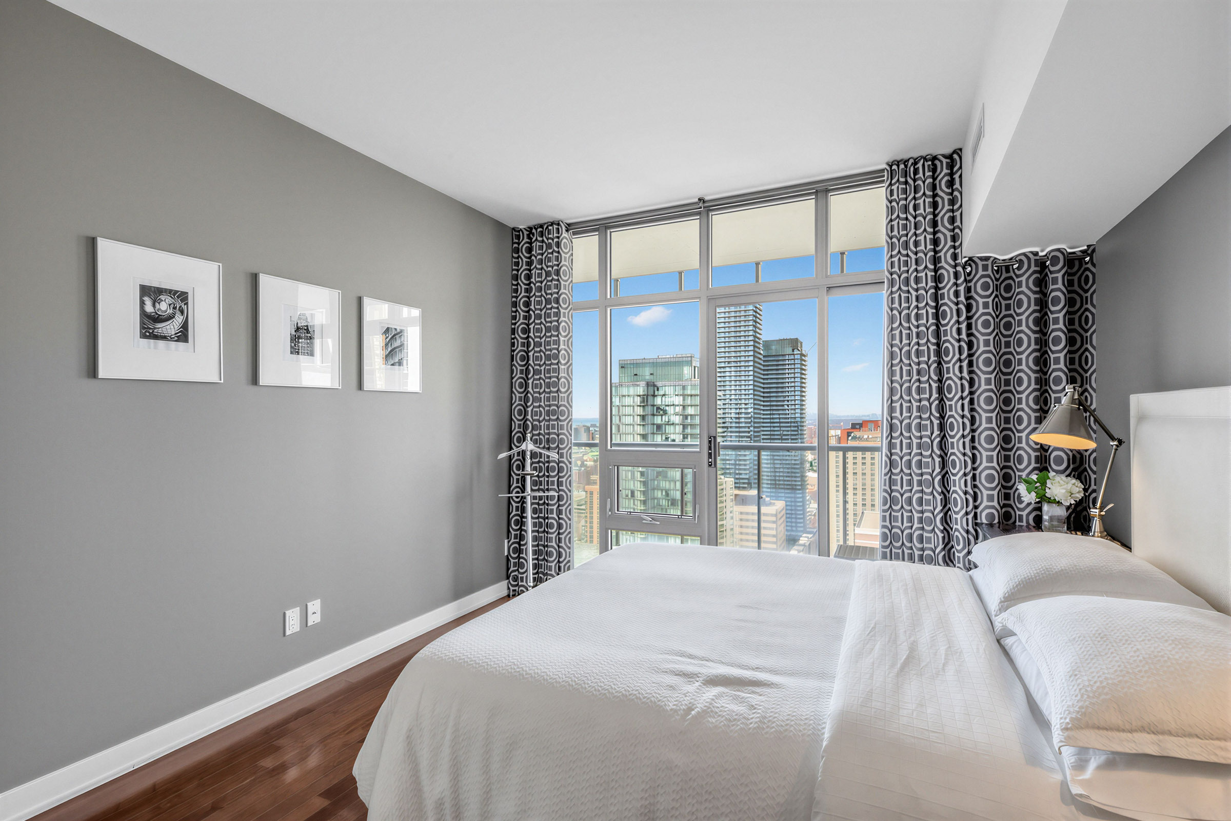 Condo primary bedroom with king-sized bed and dark gray walls with framed photographs.