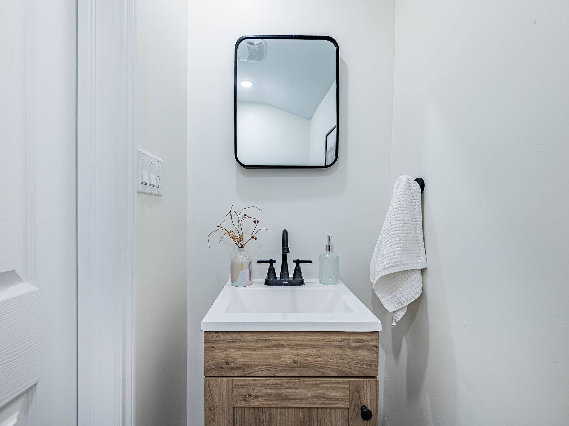 918 Ossington Ave 2-piece powder room with wall-mounted mirror and sink with wood cabinet.