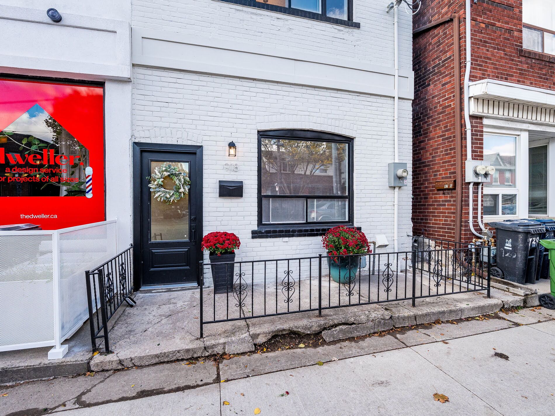918 Ossington Ave facade showing black iron gate, stone patio with planters, black door and black windows.