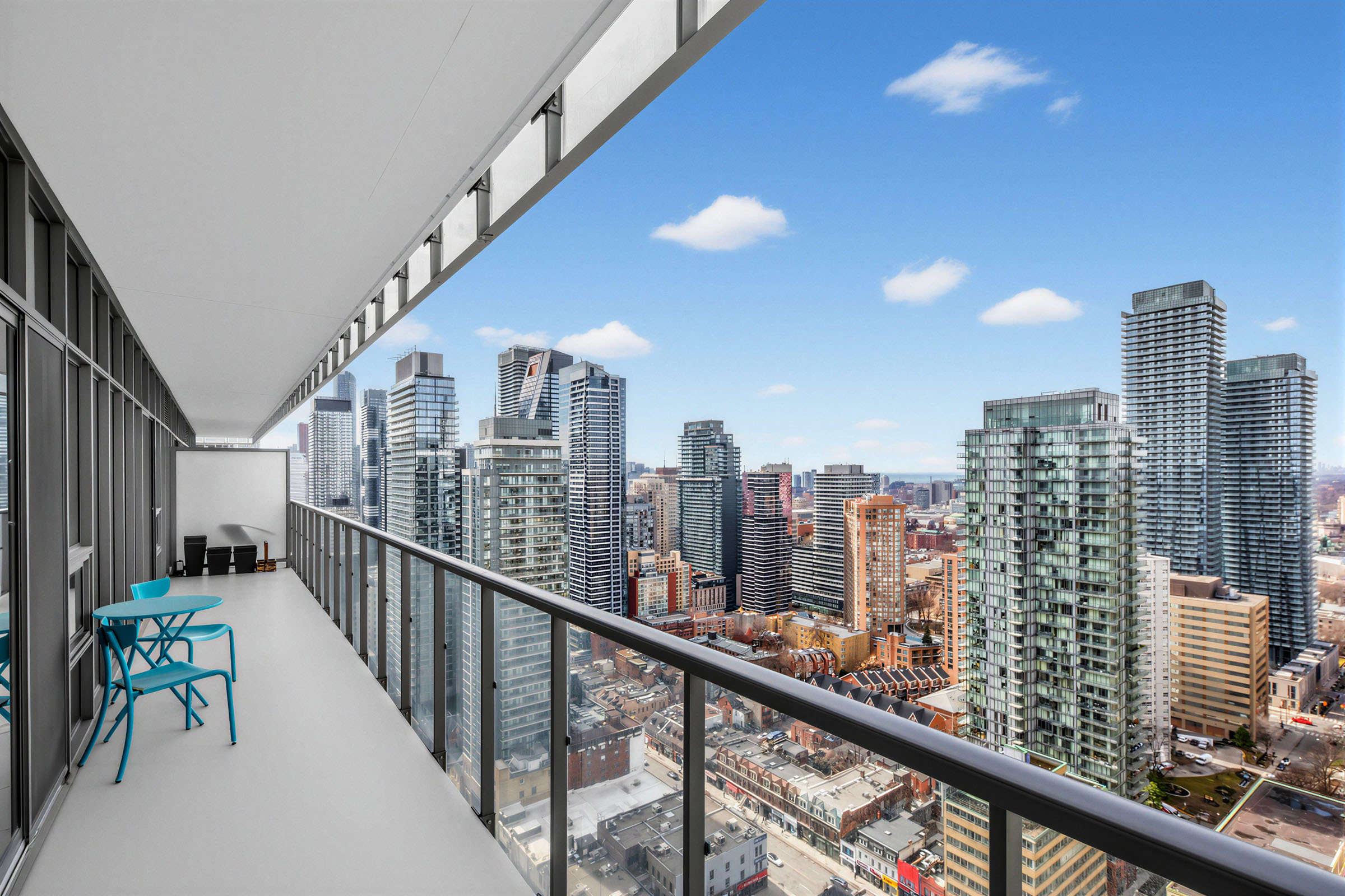 Long condo balcony with opaque divider and view of Toronto buildings.
