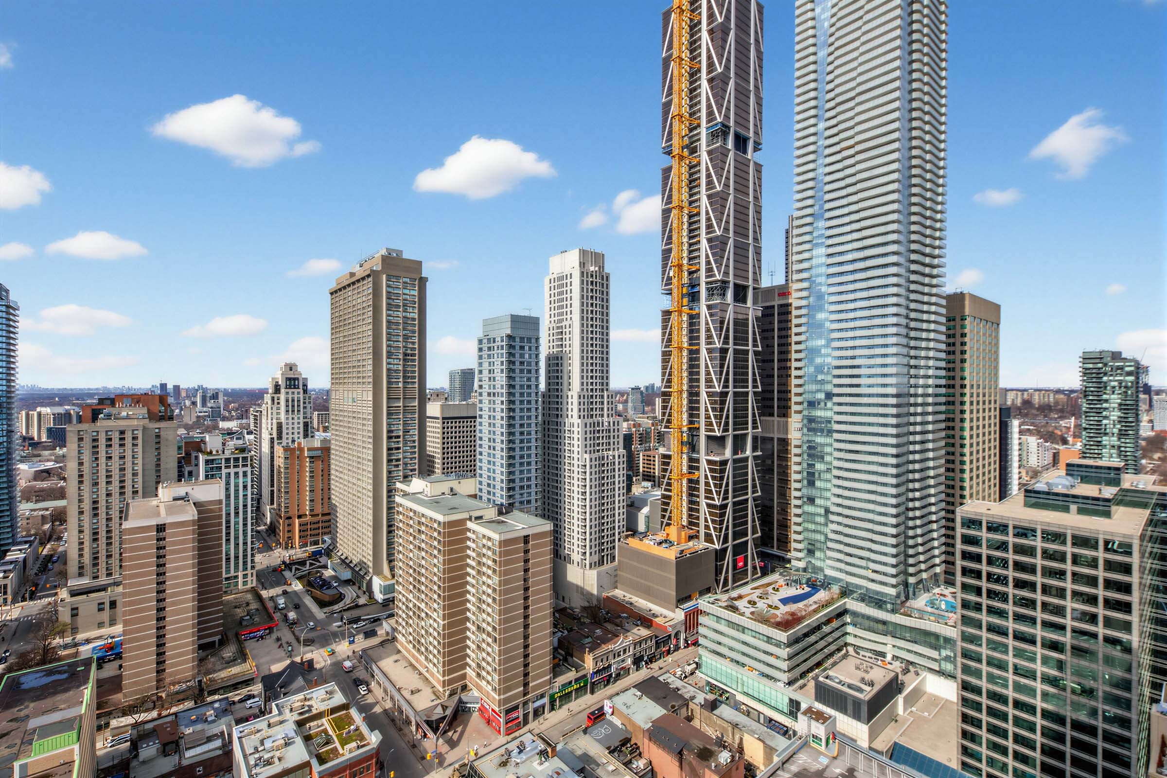 View of Toronto, including streets, shops, buildings and blue skies, from 33 Charles St E Unit 3206 balcony.