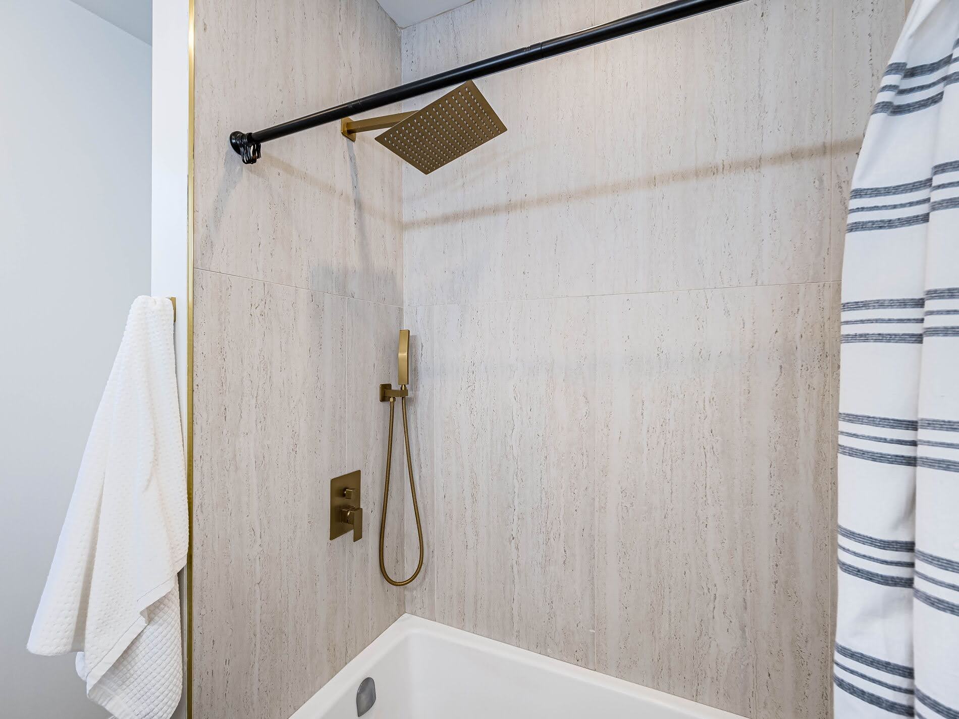 Bathroom shower with large industrial chic wall tiles and bronze fixtures.