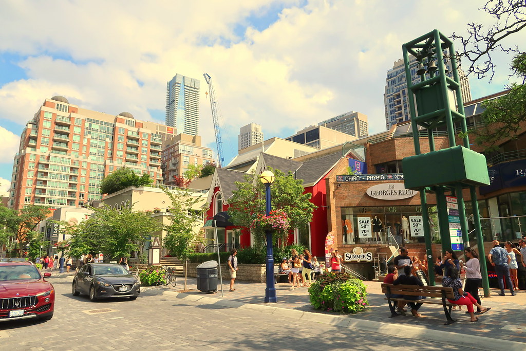 Across the street shot of people, cars, shops and buildings in Yorkville, Toronto.