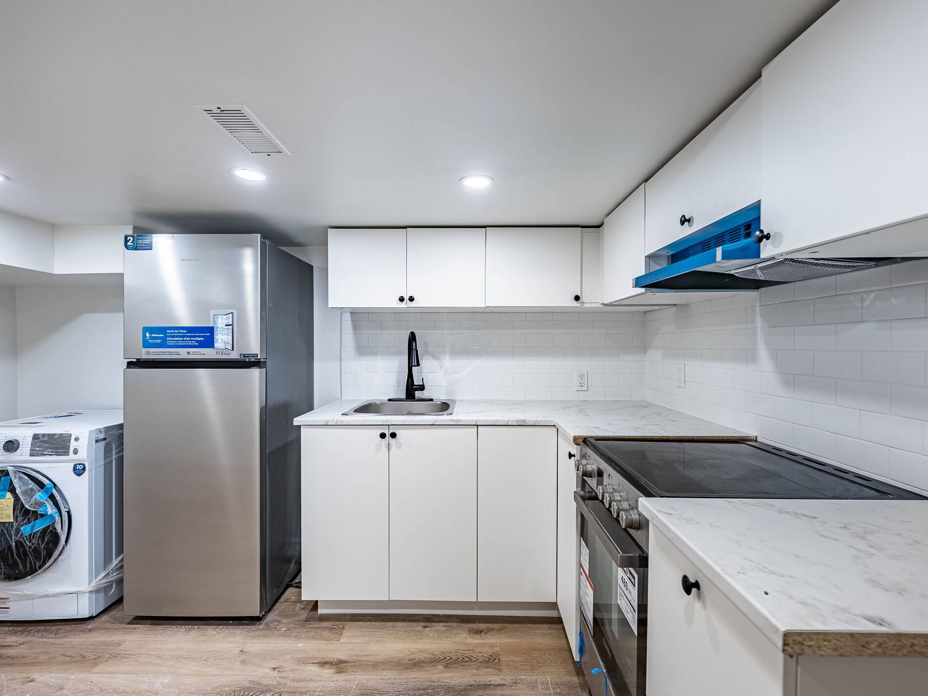 New basement kitchen with stickers and plastic.
