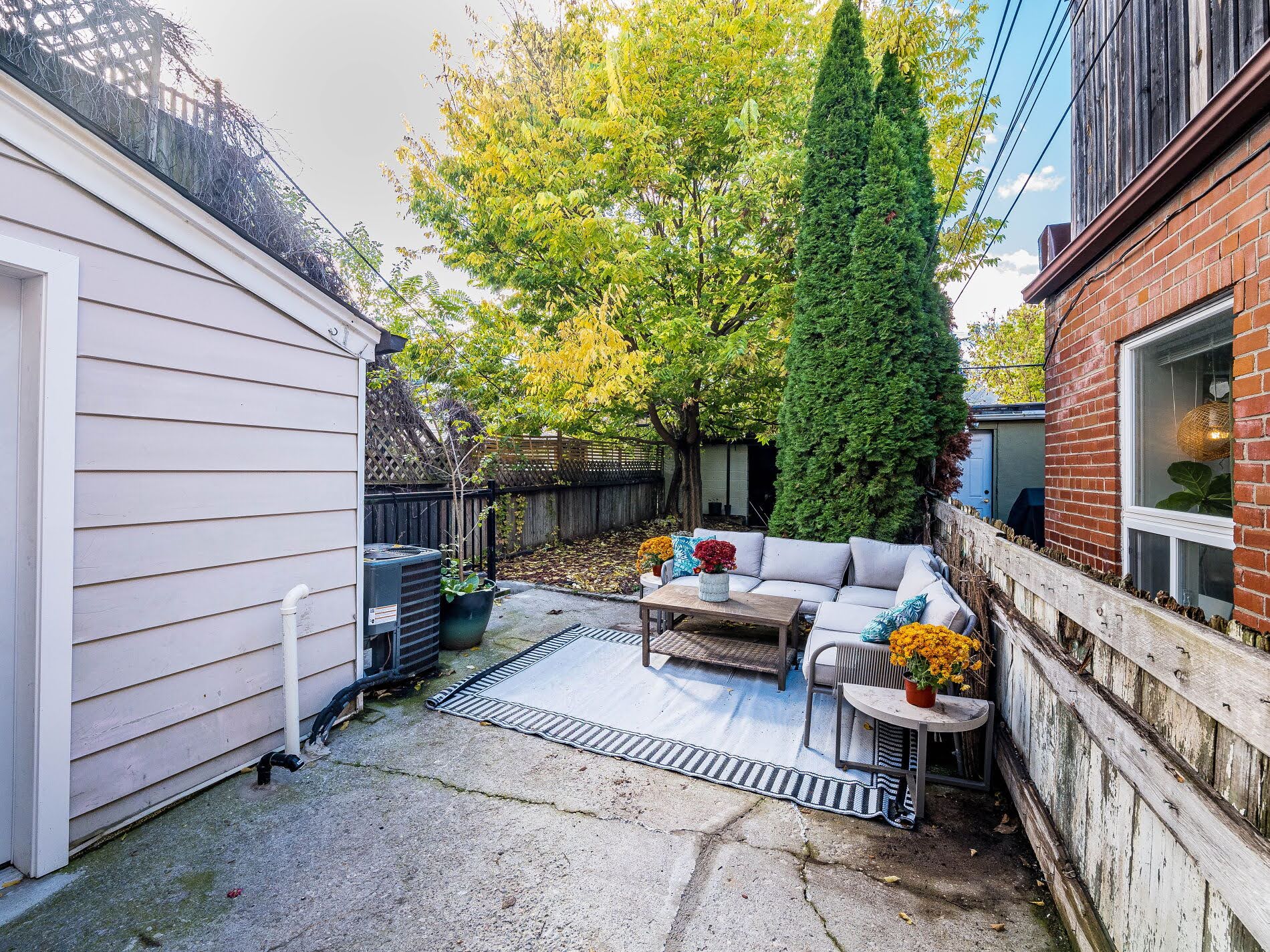 918 Ossington Ave large backyard paved patio with furniture, flowers and trees.