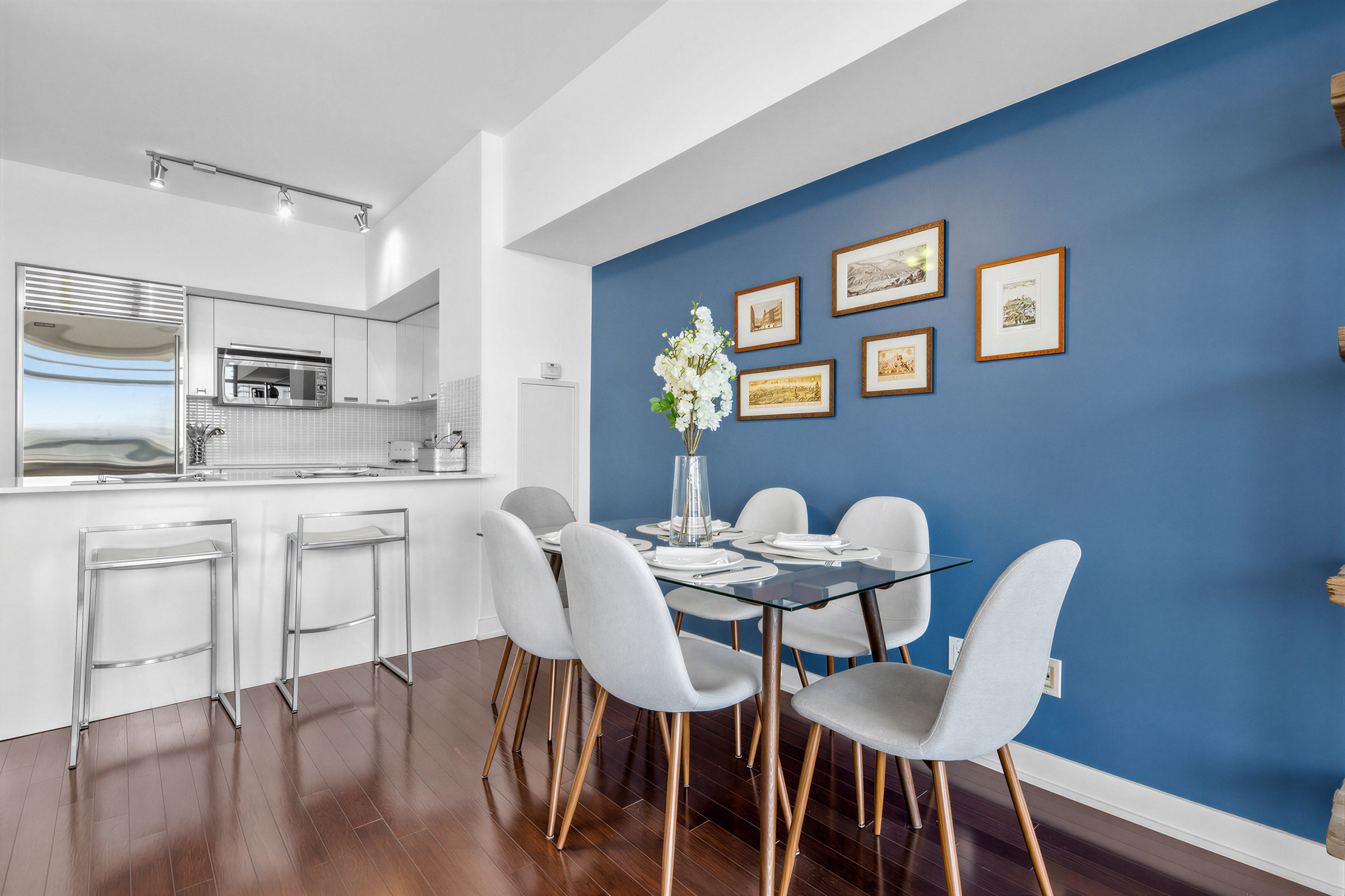 33 Charles St E Unit 3206's dining room with framed photos on blue accent wall.