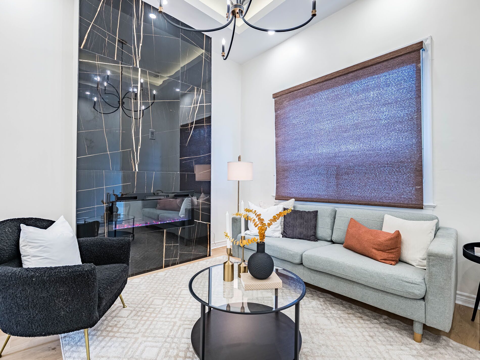 Living room with electric fireplace enclosed in sleek black-tiled feature wall.