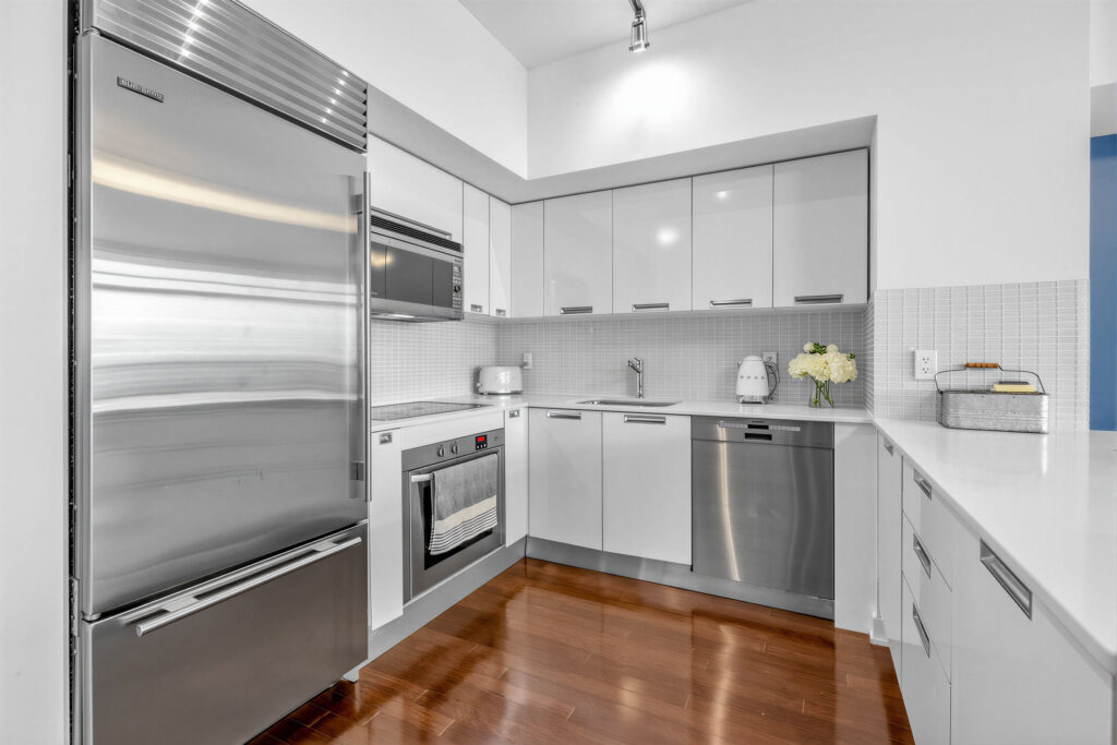 Kitchen with hardwood floors, stainless-steel appliances and ceramic backsplash.