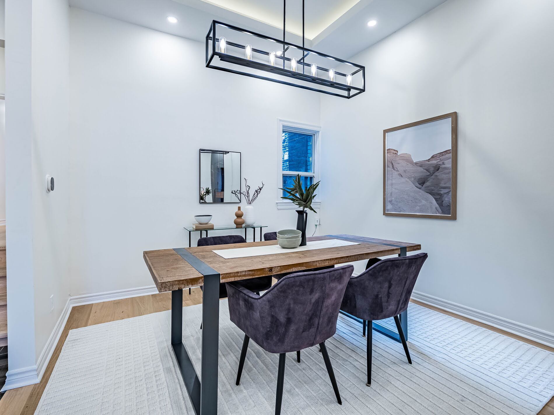 918 Ossington Ave's dining room with dining table, chairs and black linear cage chandelier.