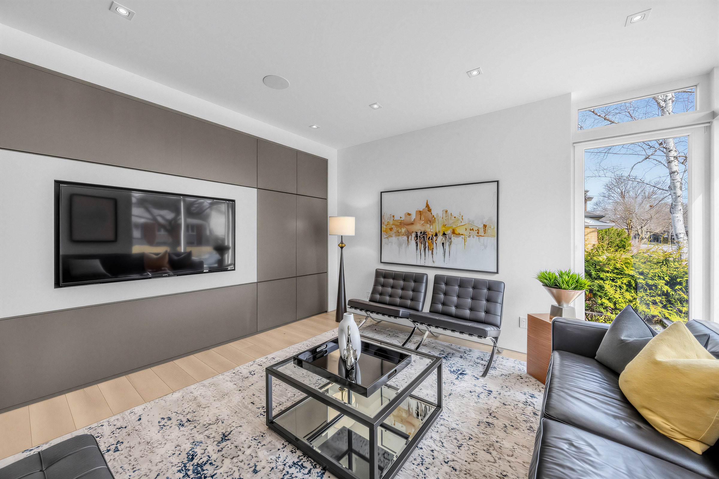 52 Burrows Ave spacious family room with modern leather furniture, carpet, hardwood floors, and a dark brown feature wall with light centre panel with TV.