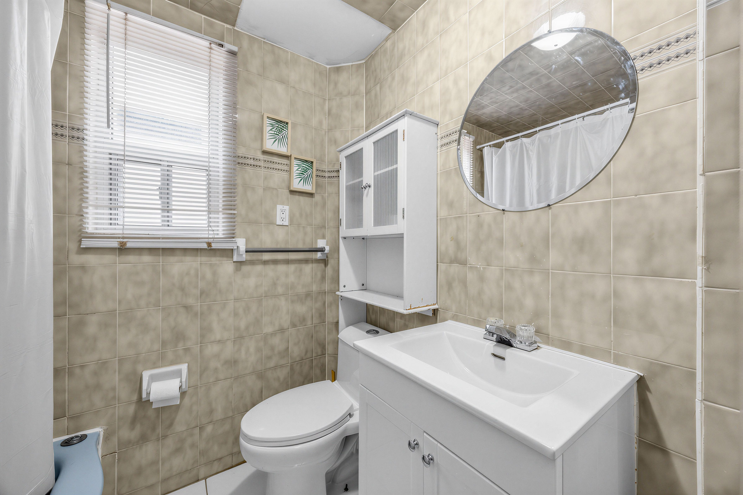 57 Shanly St 2nd floor bathroom dark beige tiled walls, silver vanity, sink with storage, and over-the-toilet wall-mounted cabinet.